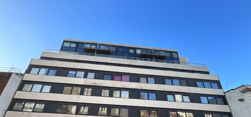 Top of a high rise block of flats. Penthouses with balcony's at the very top. Bright blue skies