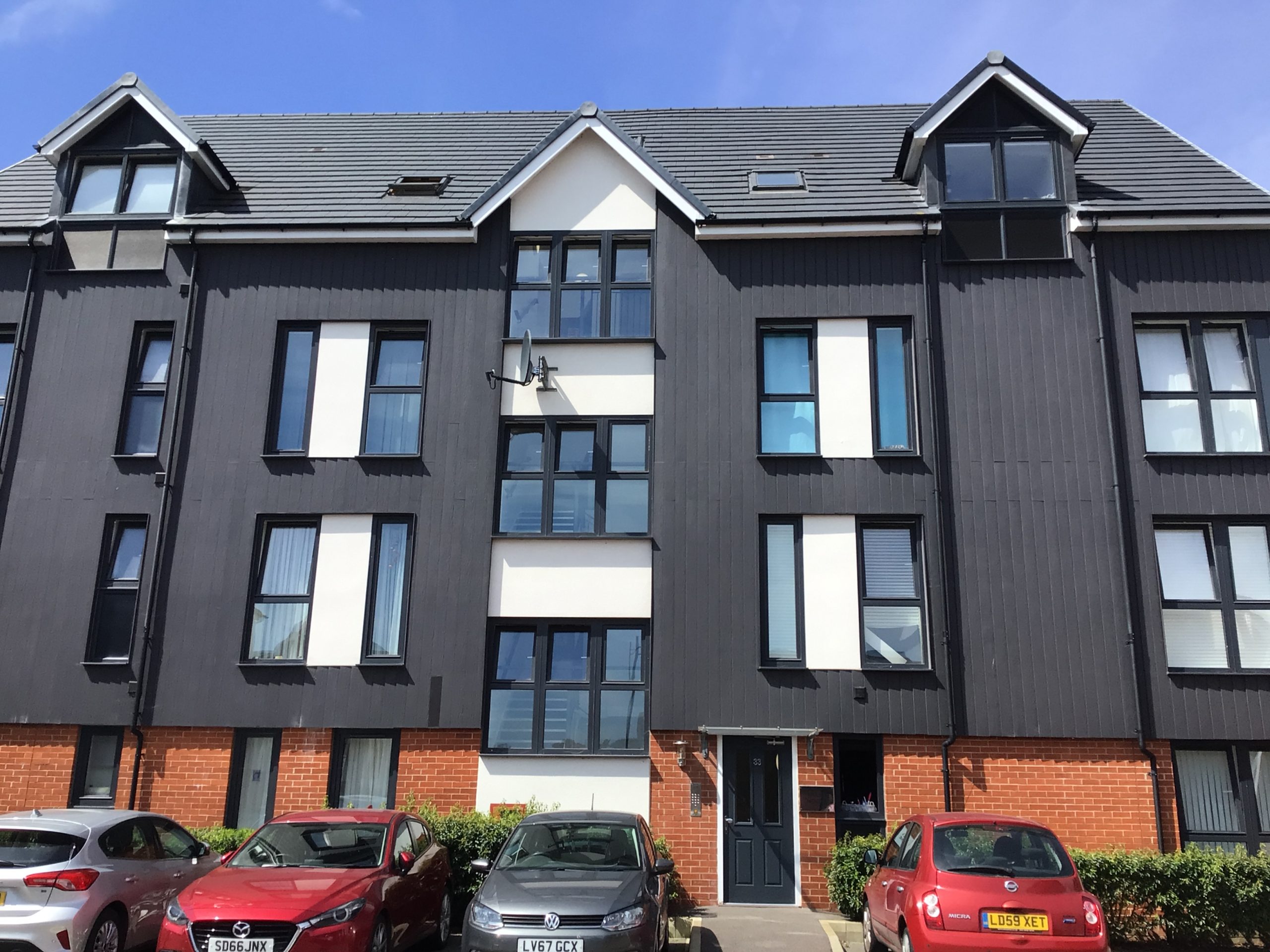 Black panels on a house with various cars in front