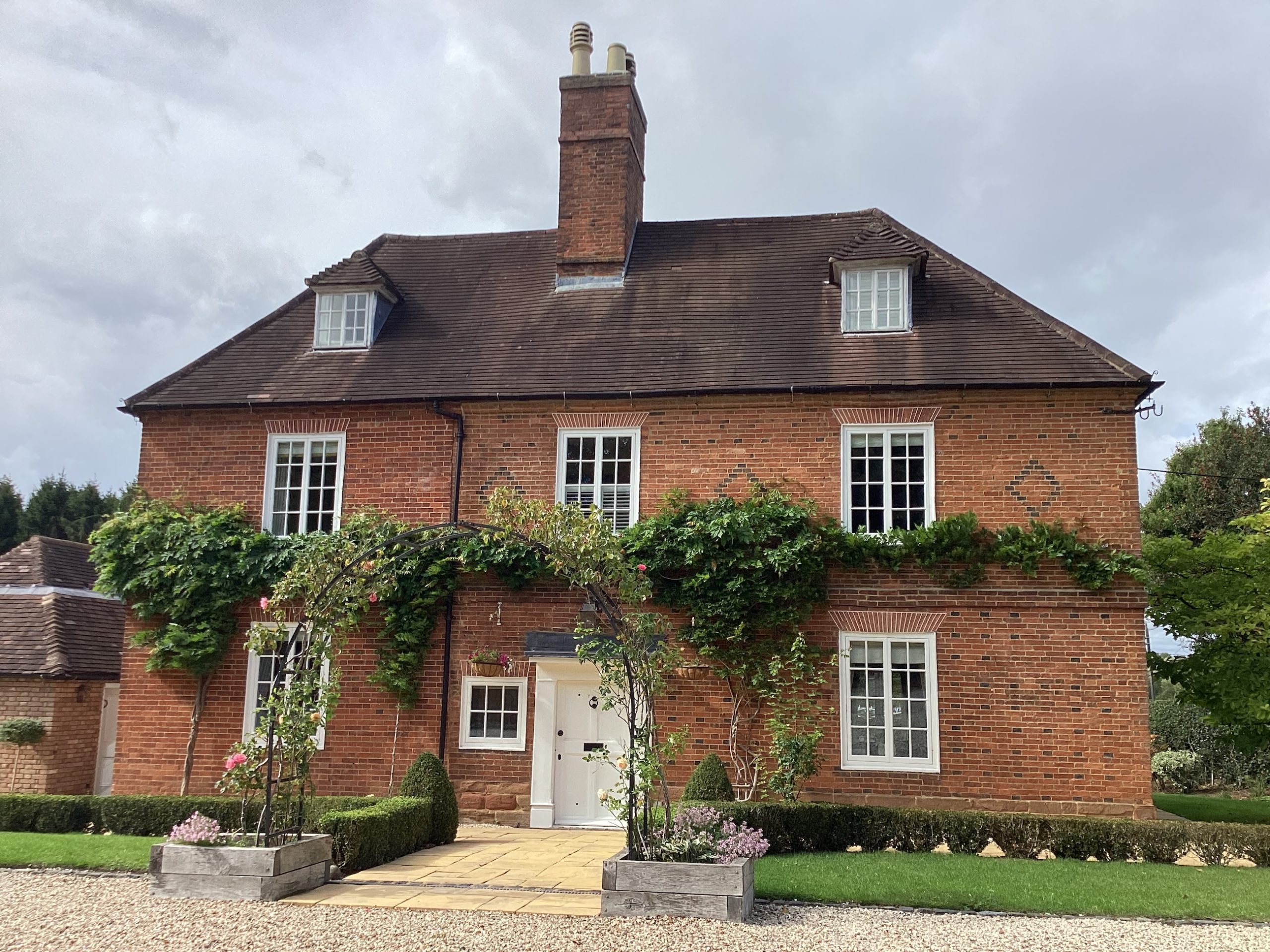 Front of large brick house with greenery