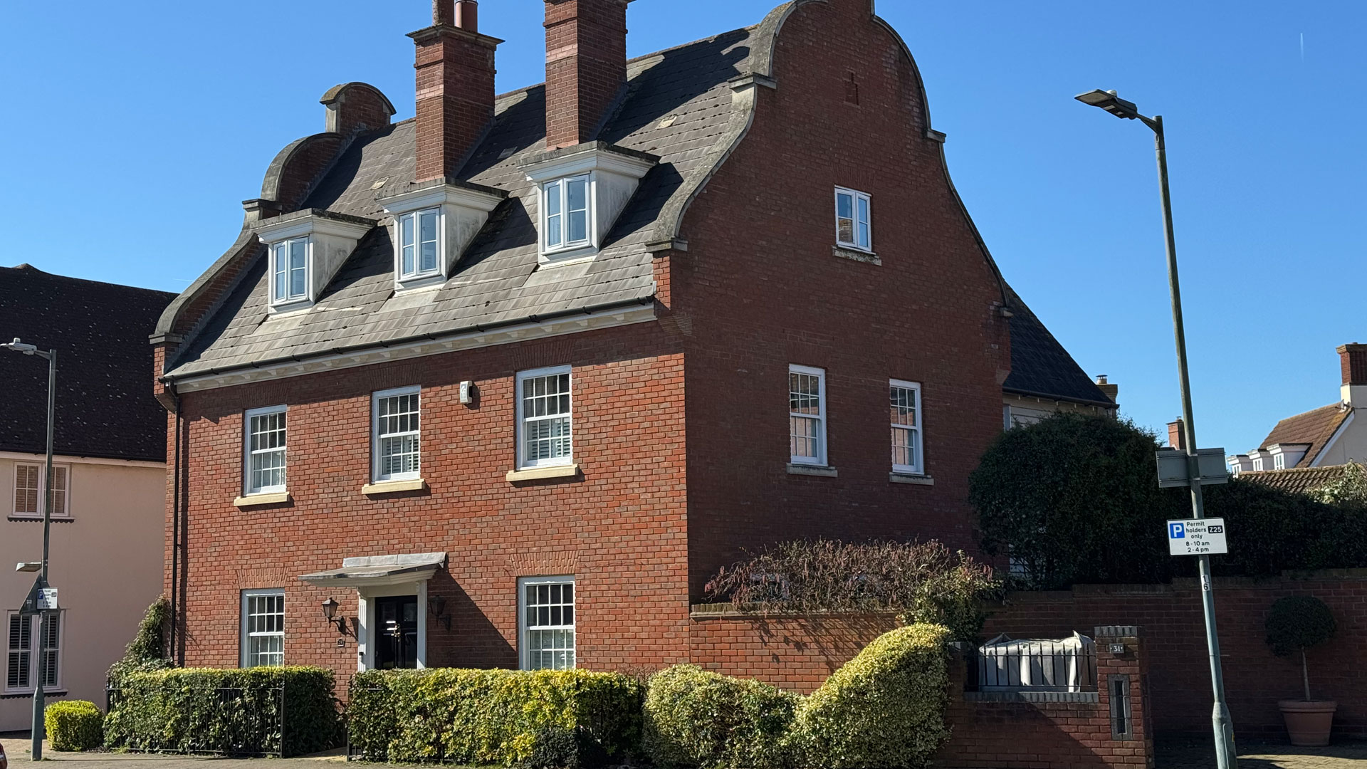 Detached large house with red brickwork and a green hedge