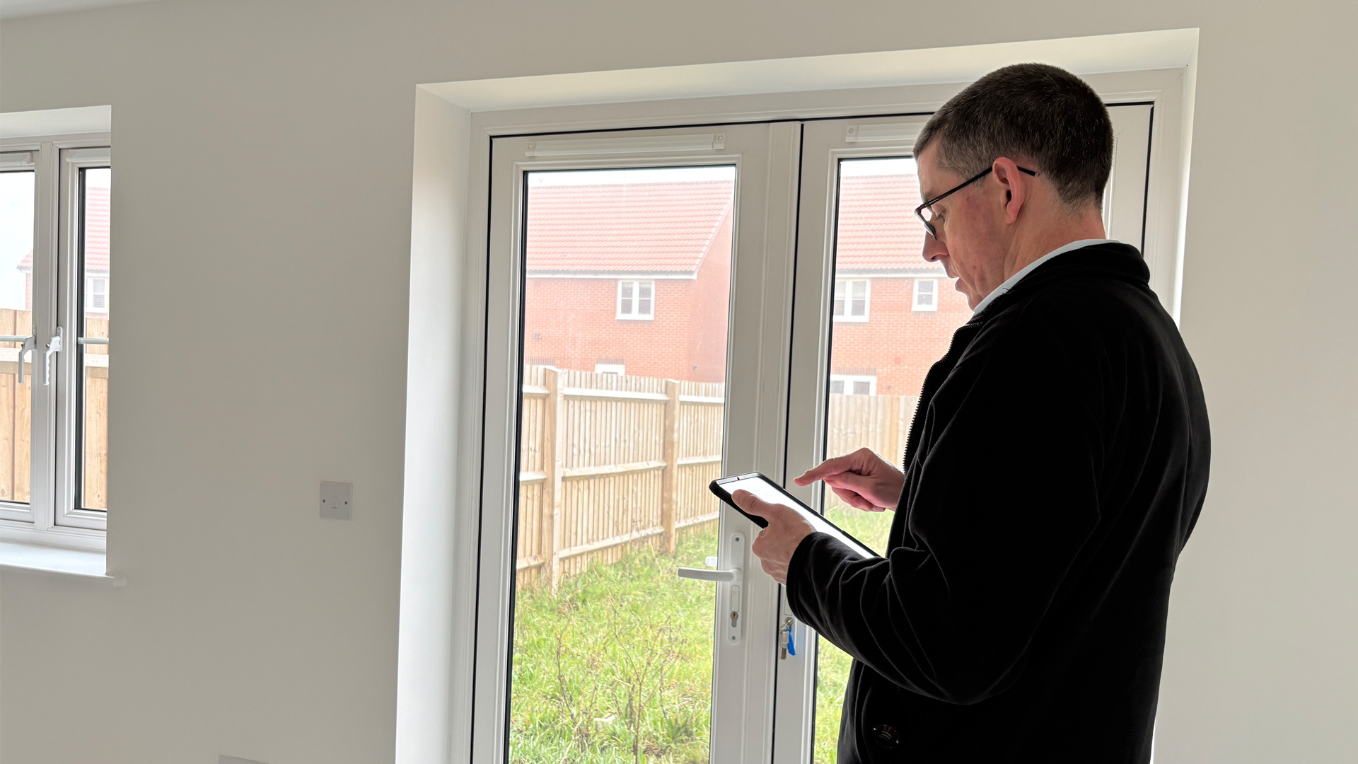 Surveyor doing a report inside a residential house with white walls and white patio door